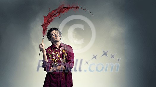 Young handsome man painter with brush in hand Young handsome man painter with brush in hand