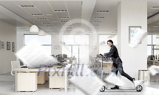Young cheerful businessman in suit riding scooter in office Young cheerful businessman in suit riding scooter in office