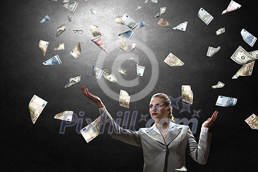 Young businesswoman standing in the rain of money banknotes Young businesswoman standing in the rain of money banknotes