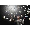 Young businesswoman standing in the rain of money banknotes