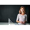 Pretty, young female student/young teacxher in front of a blackboard during class