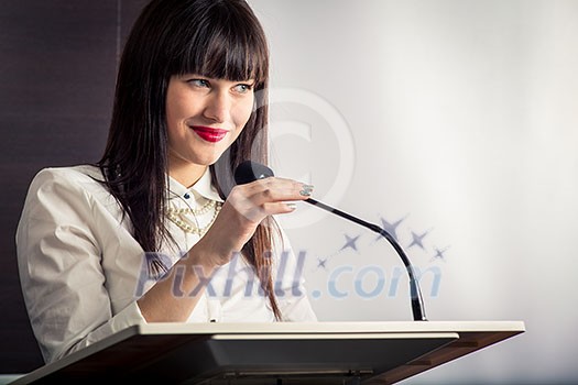 Pretty, young business woman giving a presentation in a conference/meeting setting (shallow DOF; color toned image)