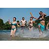 summer joy group of happy friends having  fun while running and splashing on river