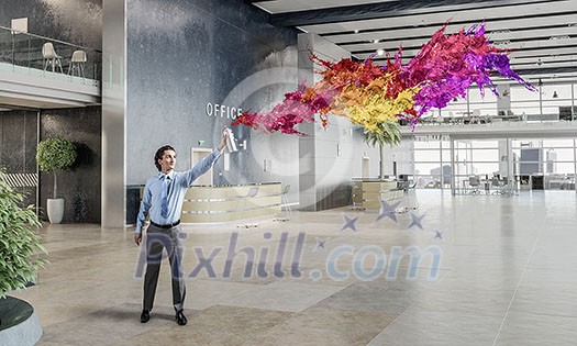 Businessman in office interior spraying paint from aerosol Businessman in office interior spraying paint from aerosol