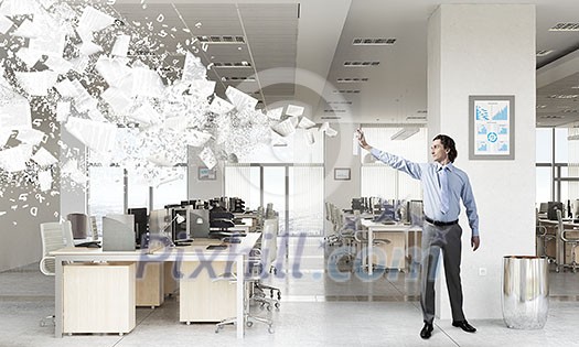 Businessman in office interior spraying paint from aerosol Businessman in office interior spraying paint from aerosol