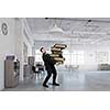 Young businessman in modern office carrying pile of books
