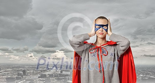 Young woman in red cape and mask covering ears with palms Young woman in red cape and mask covering ears with palms