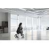 Young pretty businesswoman riding three wheeled bike in office