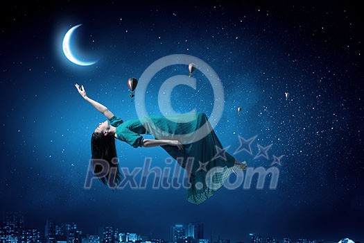 Elegant woman in green long dress floating in night sky Elegant woman in green long dress floating in night sky