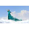 Elegant woman in green long dress walking on clouds