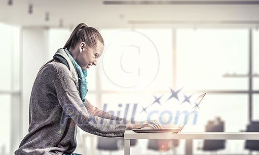Young hipster girl sitting at table and working on laptop Young hipster girl sitting at table and working on laptop