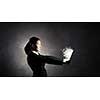 Young businesswoman holding tablet on dark background