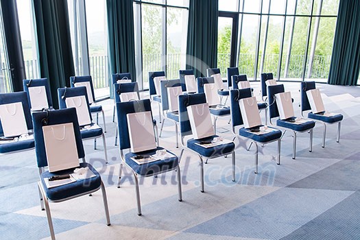 interior of big modern conference room with gifts and headphones on chairs for participants before starting a business seminar interior of big modern conference room with gifts and headphones on chairs for participants before starting a business seminar