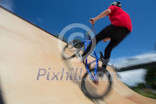 Bmx rider jumping over on a U ramp in a skatepark (motion blurred image) Bmx rider jumping over on a U ramp in a skatepark (motion blurred image)