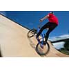 Bmx rider jumping over on a U ramp in a skatepark (motion blurred image)