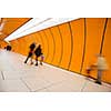People rushing through a subway corridor (motion blur technique is used to convey movement)