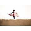 Young beautiful black girl laughs and dances outdoors with a scarf in her hands in a meadow during sunset