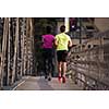 healthy young multiethnic couple jogging across the bridge in the city at early morning with sunrise in background