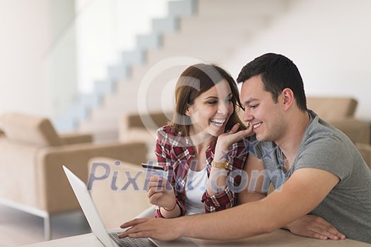 happy young couple buying online using laptop a computer and a credit card in their luxury home villa happy young couple buying online using laptop a computer and a credit card in their luxury home villa