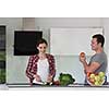 Young handsome couple in the kitchen  beautiful woman preparing a salad while the man eating an apple