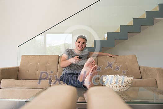 young handsome man enjoying free time watching television with popcorn in his luxury home villa young handsome man enjoying free time watching television with popcorn in his luxury home villa