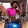 happy african american woman with a curly afro hairstyle in a  gym relaxing after pilates workout