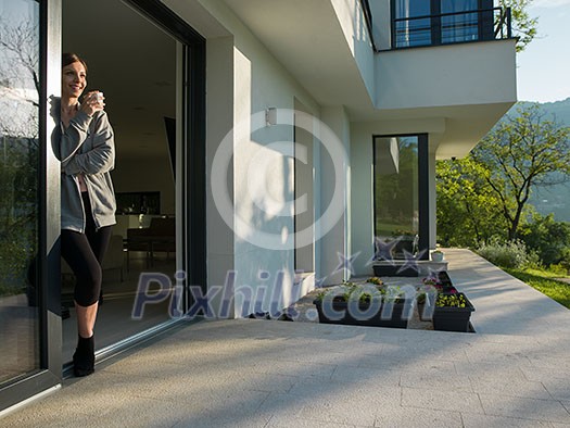 portrait of a young beautiful successful woman drinking coffee in the doorway of her luxury home villa portrait of a young beautiful successful woman drinking coffee in the doorway of her luxury home villa