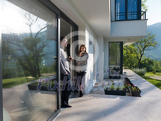 young beautiful handsome couple enjoying morning coffee on the door of their luxury home villa young beautiful handsome couple enjoying morning coffee on the door of their luxury home villa