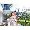 Young beautiful couple in bathrobes are enjoying morning coffee in front of their luxury home villa