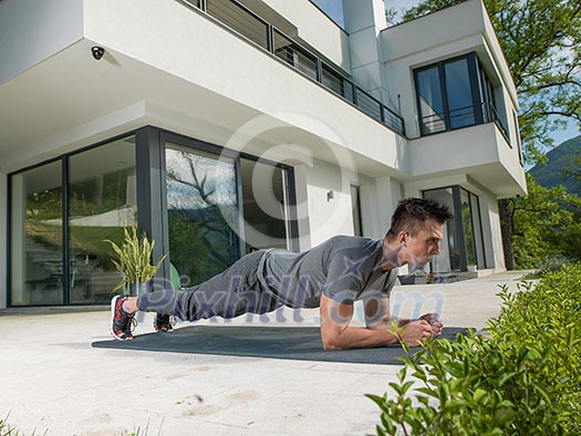 young handsome man doing morning yoga exercises in front of his luxury home villa young handsome man doing morning yoga exercises in front of his luxury home villa