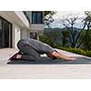 young handsome man doing morning yoga exercises in front of his luxury home villa