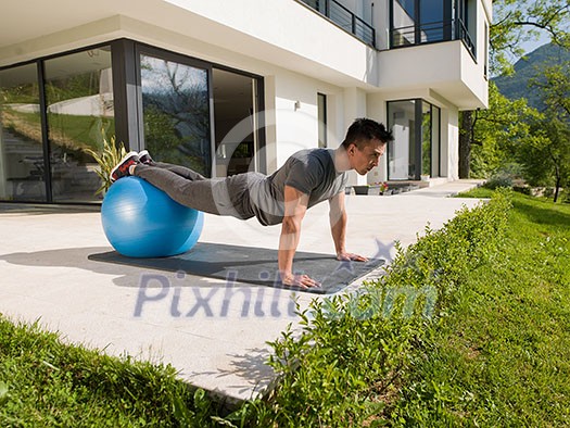 young handsome man doing morning yoga exercises in front of his luxury home villa young handsome man doing morning yoga exercises in front of his luxury home villa