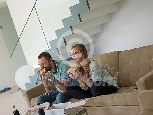 young handsome couple cheerfully spending time while eating pizza in their luxury home villa