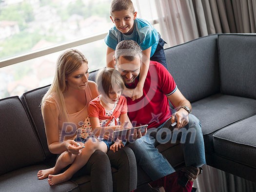 Happy Young Family Playing Together with tablet at home sitting on the sofa Happy Young Family Playing Together with tablet at home sitting on the sofa