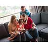Happy Young Family Playing Together with tablet at home sitting on the sofa