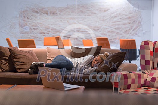 A young casual business woman sleeping on a sofa during a work break in a creative office A young casual business woman sleeping on a sofa during a work break in a creative office