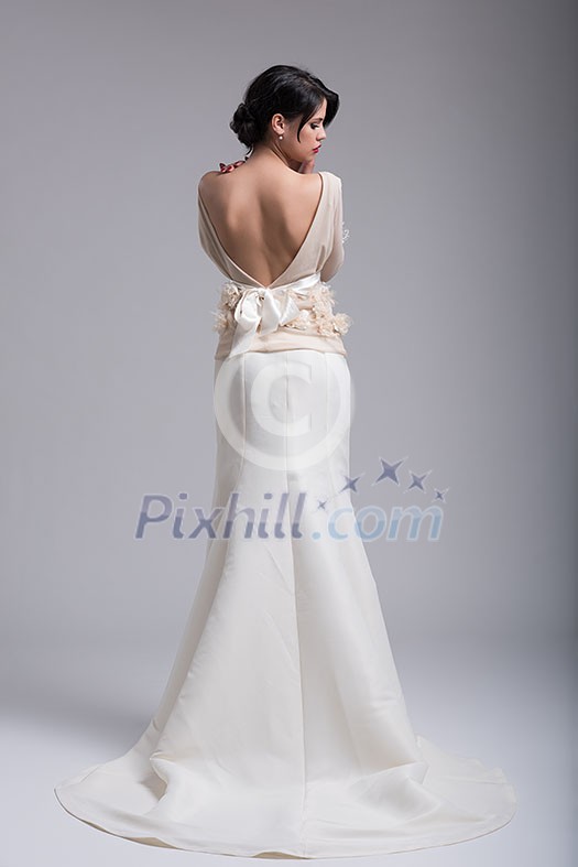 Rear view of a beautiful young bride in a wedding dress isolated on a white background