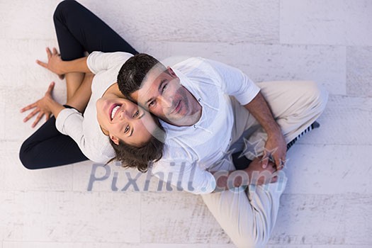 top view of Cheerful young couple sitting with back to each other on floor top view of Cheerful young couple sitting with back to each other on floor