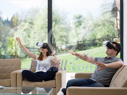 Couple using virtual reality headset in living room at home people playing game with new trends technology Couple using virtual reality headset in living room at home people playing game with new trends technology