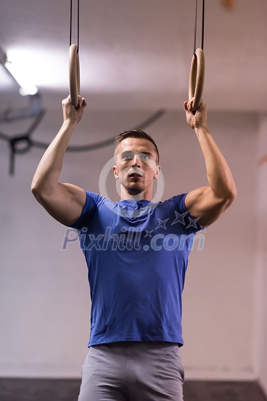 Fitness handsome man doing dipping exercise using rings in the gym Fitness handsome man doing dipping exercise using rings in the gym