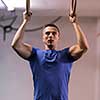 Fitness handsome man doing dipping exercise using rings in the gym