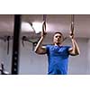 Fitness handsome man doing dipping exercise using rings in the gym
