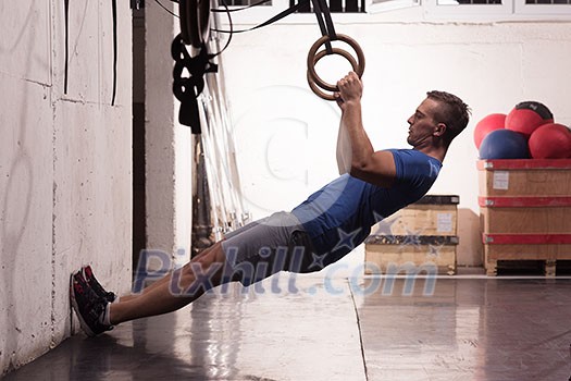 Fitness handsome man doing dipping exercise using rings in the gym Fitness handsome man doing dipping exercise using rings in the gym