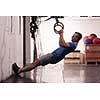 Fitness handsome man doing dipping exercise using rings in the gym