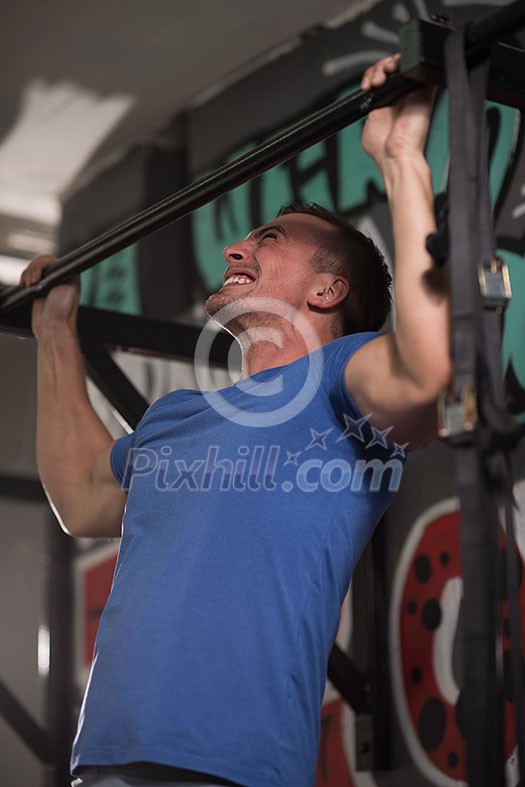 strong young man doing pull ups on a bar in a gym strong young man doing pull ups on a bar in a gym