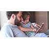 Father Daughter sitting in sofa  playing games on tablet