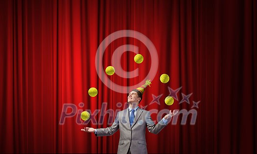 Young businessman in cap on stage juggling with balls Young businessman in cap on stage juggling with balls