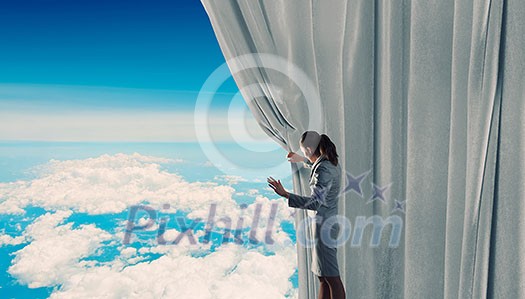 Young businesswoman opening stage curtain to another reality Young businesswoman opening stage curtain to another reality