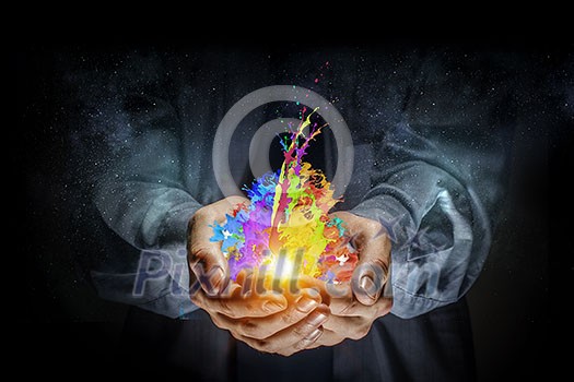 Close up of hand holding splashes of colorful paint Close up of hand holding splashes of colorful paint