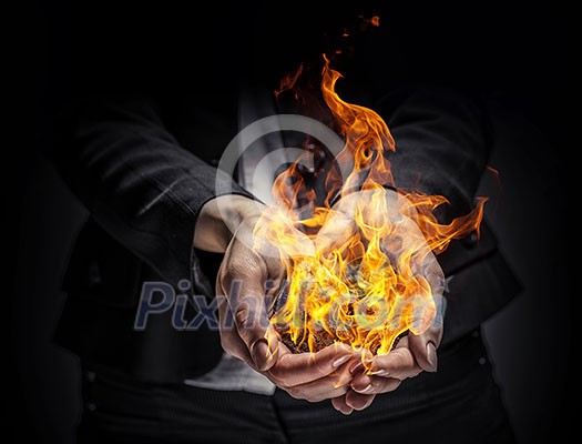Young businesswoman holding fire flames in palm Young businesswoman holding fire flames in palm